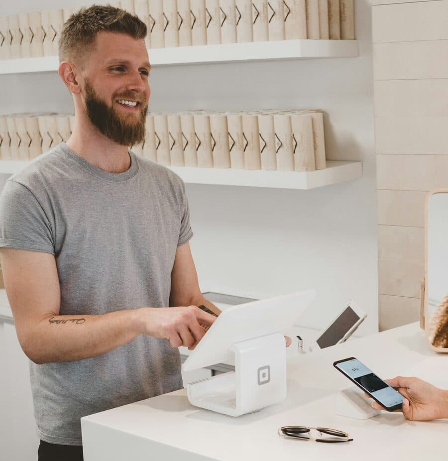 A shopkeeper taking a contactless payment at a white counter