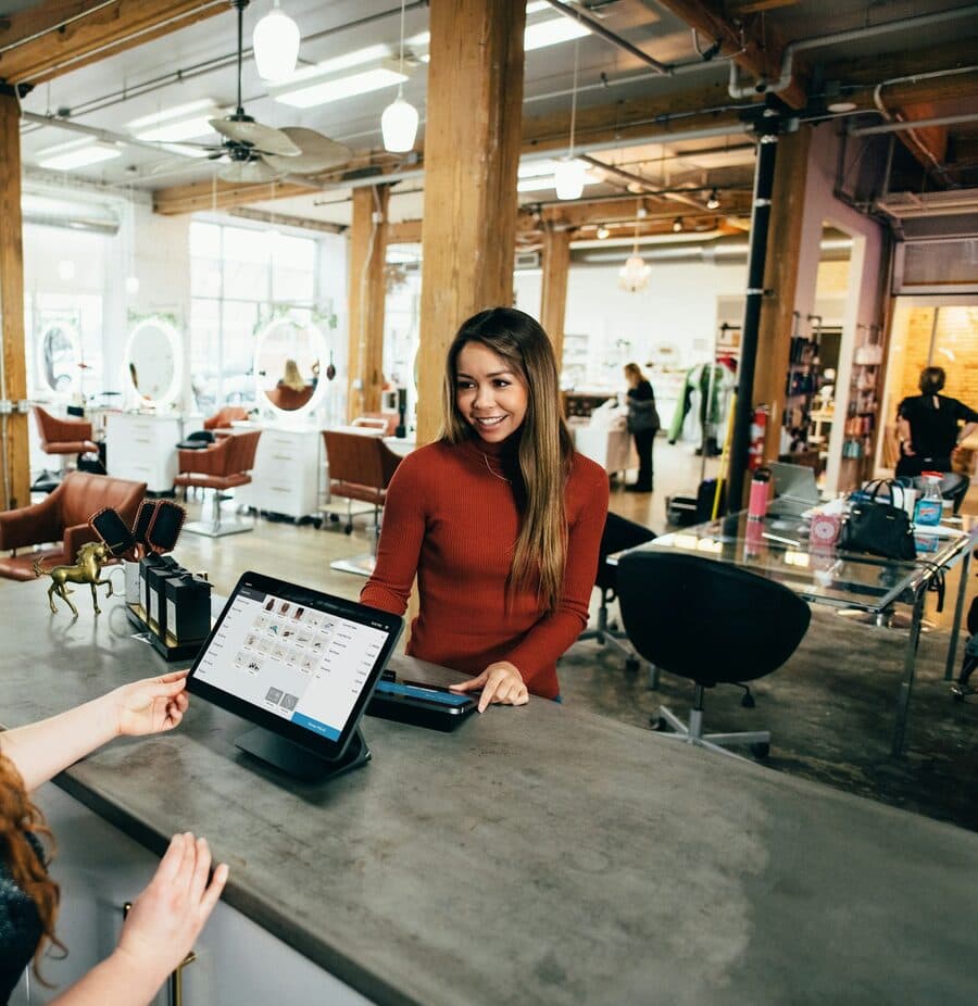 A salon receptionist taking a card payment on a tablet