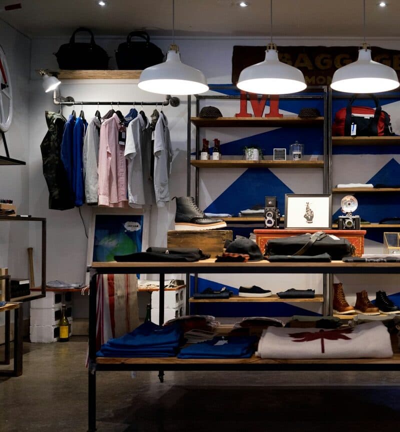 A rail of shirts and shelves of stock in a small clothes shop